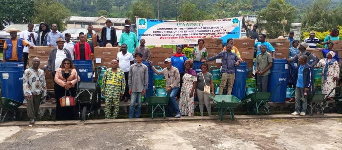 Community members standing behind farm tools and equipment received at a distribution event