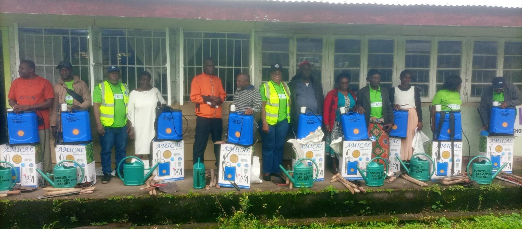 Farmers standing with knapsack sprayers and input bags received at a distribution